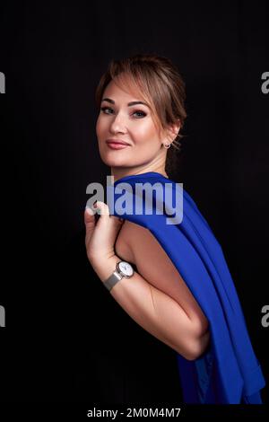 une femme adulte caucasienne a jeté une veste bleue sur ses épaules sur un fond noir. Photo de haute qualité Banque D'Images