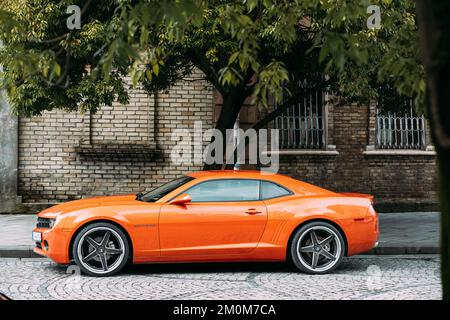 Voiture Orange Chevrolet Camaro garée dans la rue. Sixième génération Banque D'Images