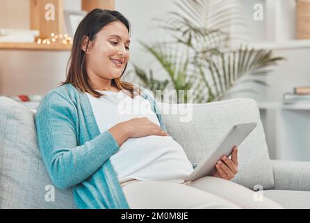 Diffusez des films, une femme enceinte et une tablette regardant des vidéos et défilant sur les réseaux sociaux tout en se détendant sur le canapé seul à la maison. Heureux, souriant ou Banque D'Images