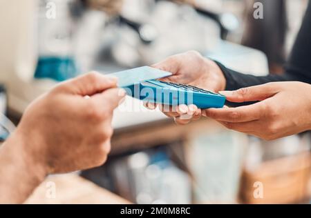 Gros plan d'un employé acceptant un paiement par carte de crédit sans contact à l'aide de la technologie nfc d'un client dans un café ou un magasin. Mains de l'homme tapotant la carte Banque D'Images