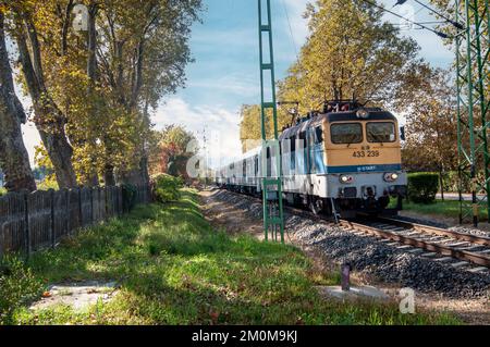 Le train de voyageurs traverse un passage à niveau en milieu rural. Après que la barrière de circulation a été abaissée photographiée au lac Balaton, en Hongrie Banque D'Images