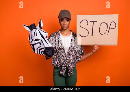 Photo d'une personne sérieuse tenir le carton affiche arrêter la cruauté envers les animaux isolé sur fond de couleur orange Banque D'Images