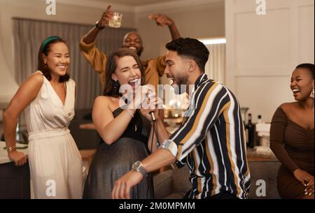 Soirée entre amis, fête et karaoké à la maison pour un événement social amusant ou pour se réunir en fête pour le nouvel an. Des gens heureux qui célèbrent Banque D'Images