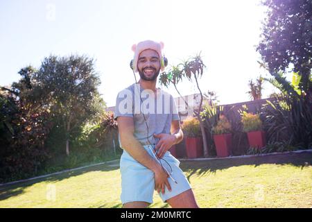 Musique, homme ivre danse à la fête radio en streaming avec casque dans le jardin extérieur. Fête du nouvel an, événement et homme écoutant la chanson drôle ou Banque D'Images