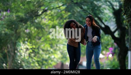 Deux jeunes femmes diverses rient ensemble tout en marchant dans la rue Banque D'Images
