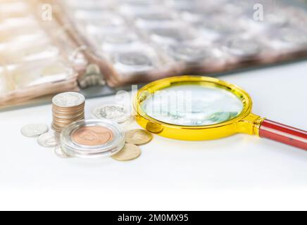 Collection de pièces album numismatique avec loupe sur la table. Banque D'Images