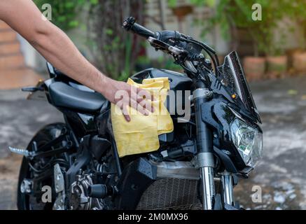 Moto de nettoyage Biker man , polie sur le réservoir de carburant dans la zone de buanderie. Banque D'Images