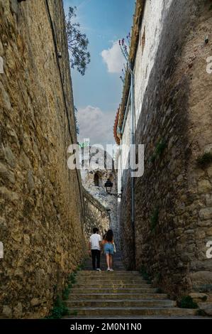 les jeunes marchent sur un escalier dans une ruelle étroite d'une ville médiévale sous un ciel bleu avec des murs couverts de pierre Banque D'Images