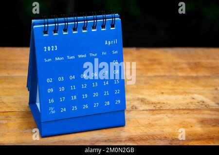 Avril 2023 calendrier de bureau bleu sur fond de table en bois avec espace personnalisable pour le texte. Banque D'Images