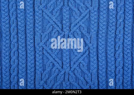 Fond bleu tricoté. Grand tissu tricoté avec un motif. Gros plan d'une couverture tricotée. Banque D'Images