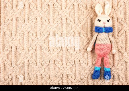 Jouet en bonneterie lièvre ou lapin pour enfants sur un tissu beige tricoté. Le symbole de 2023. Banque D'Images