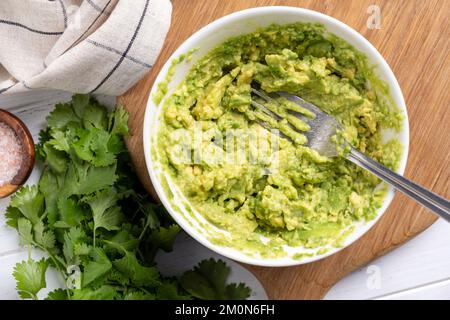 Purée d'avocat dans un bol. Guacamole mexicaine, sauce avocat pour toasts. Vue du dessus de la table Banque D'Images