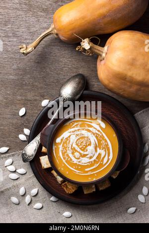 Soupe de potiron à la crème et aux graines de sésame dans un bol en céramique marron sur fond de bois. Flat lay, vue de dessus. Banque D'Images
