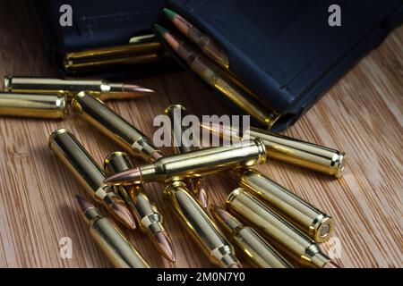 Balles de 5,56x45mm (.223) AR-15 en vrac disposées à côté de deux magasins chargés pleins de munitions Banque D'Images