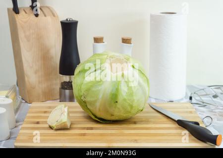 Tête verte de chou sur une planche à découper avec un couteau - table de cuisine en arrière-plan Banque D'Images