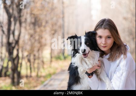 Femme caucasienne embrassant la frontière collie dans le parc d'automne. Portrait d'une fille avec un chien. Banque D'Images