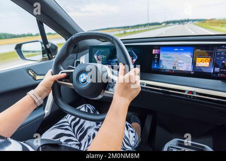 Vue rapprochée d'une femme conduisant une nouvelle voiture électrique BMW IX 40. Suède. Uppsala. Banque D'Images