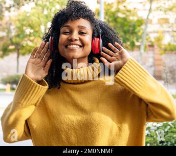 Une femme afro-américaine joyeuse qui écoute de la musique avec un casque dans une ville Banque D'Images