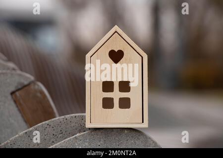 Une petite maison en bois se dresse sur un fond rayé en pierre ondulée, une maison de rêve Banque D'Images