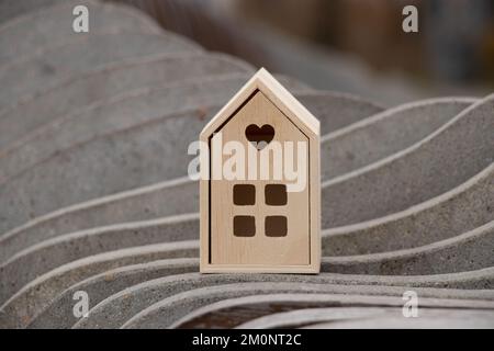 Une petite maison en bois se dresse sur un fond rayé en pierre ondulée, une maison de rêve Banque D'Images