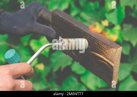 Un homme brûle des planches avec le feu d'un brûleur à gaz. Banque D'Images