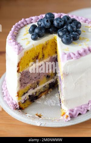 Gâteau d'anniversaire ou de mariage au citron et aux myrtilles avec une tranche coupée. Banque D'Images