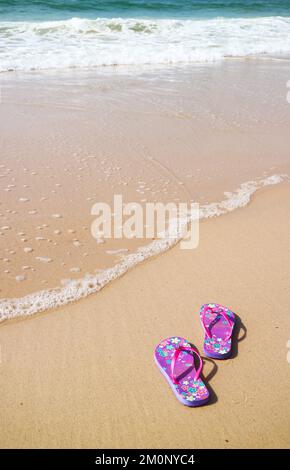 Une paire de sandales à tongs violettes sur la plage avec le lavage à l'arrière, plage de Copacabana, Brésil Banque D'Images