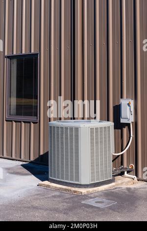 Image verticale montrant un compresseur de climatisation non étiqueté à l'extérieur d'une fenêtre de bureau. Banque D'Images