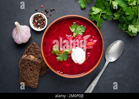 Borscht de betterave à la crème sure, à l'ail et au pain de seigle sur fond de pierre noire. Vue de dessus. Culture ukrainienne Banque D'Images