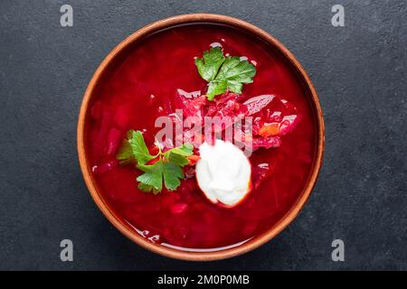 Soupe de betteraves Borscht à la crème aigre dans un bol, isolée sur une table en béton noir. Vue de dessus Banque D'Images