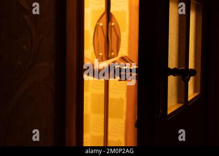 La main de la femme ouvre la porte dans l'obscurité à la maison, bouton de porte Banque D'Images