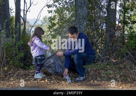 Père et fille dans les bois collectant des bouteilles en plastique. Nettoyage et recyclage de la nature. La sauvegarde de la planète. Banque D'Images