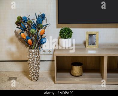 Intérieur. Vase décoratif. Meuble de téléviseur en bois. Fleur verte. Cadre photo. Banque D'Images