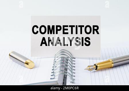 Concept financier et commercial. Sur la table se trouve un carnet, un stylo et une carte de visite avec l'inscription - ANALYSE DE LA CONCURRENCE Banque D'Images