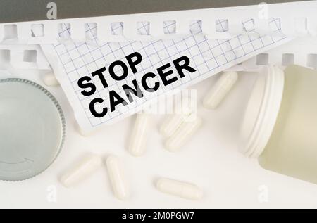 Médecine et concept de santé. Sur la table est un pot ouvert de pilules et une feuille de papier avec l'inscription - Stop cancer Banque D'Images