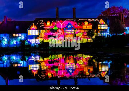 Le bâtiment du laboratoire est illuminé de lumières colorées qui se reflètent dans le canal de Jellicoe, événement de la lueur de Noël 2022 à RHS Garden Wisley, Surrey Banque D'Images