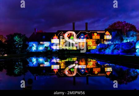 Le bâtiment du laboratoire est illuminé de lumières colorées qui se reflètent dans le canal de Jellicoe, événement de la lueur de Noël 2022 à RHS Garden Wisley, Surrey Banque D'Images