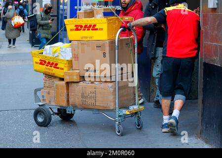 Un livreur DHL entre dans un bâtiment de Midtown Manhattan avec un camion plein de colis. Banque D'Images