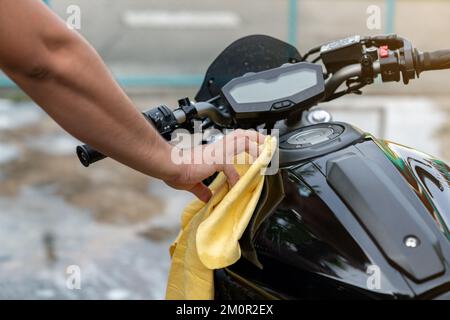 Nettoyage de moto, main de youngman avec tissu jaune laver une moto dans la buanderie. Banque D'Images