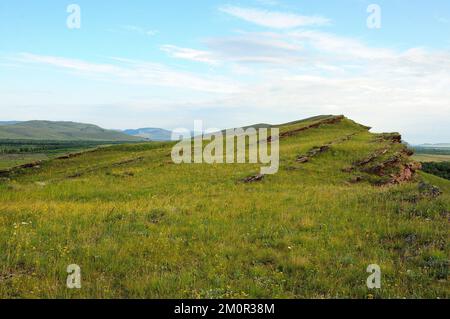 Hautes collines avec falaises abruptes dans la steppe sans fin sous un ciel chaud d'été. Coffres de montagne, Khakassia, Sibérie, Russie. Banque D'Images