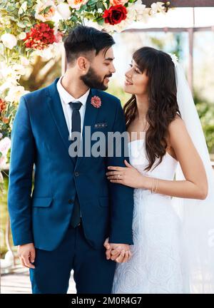 Je suis tellement amoureux de vous. un jeune couple affectueux et jeune, souriant les uns les autres tout en tenant les mains le jour de leur mariage. Banque D'Images