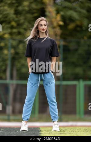 Mettre la femme blonde dans de grands vêtements posant à l'extérieur Banque D'Images