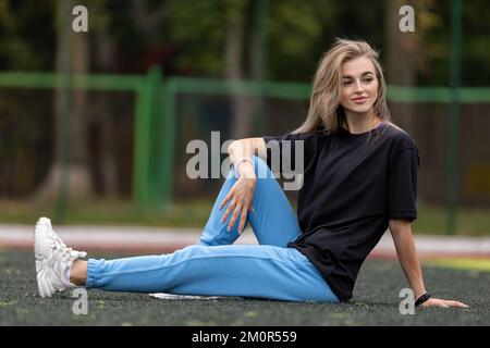 Mettre la femme blonde dans de grands vêtements posant à l'extérieur Banque D'Images