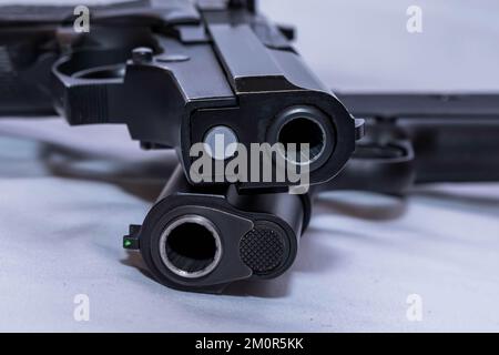 Deux pistolets noirs empilés l'un sur l'autre, un calibre 40 et un calibre 45 sur fond blanc Banque D'Images
