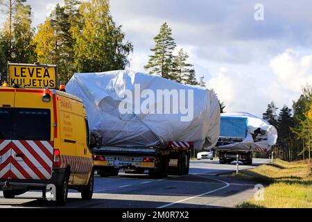 Des véhicules pilotes et d'escorte ont aidé deux camions lourds transportant des bâches couvertes de larges charges. Vue arrière. Raasepori, Finlande. 23 septembre 2022 Banque D'Images