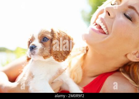 Mon chiot me rend si heureux. Spectacle d'une belle femme riante tenant un chiot adorable dehors. Banque D'Images