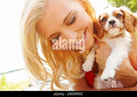 Des marionnettes. une belle blonde souriante tenant son chiot tout en appréciant une journée dehors. Banque D'Images