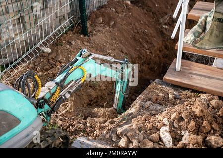 Une minipelle creuse une tranchée pour poser les tuyaux. Gros plan d'une pelle hydraulique creusant une tranchée profonde. Une pelle hydraulique creuse une tranchée dans la campagne pour déposer un Banque D'Images