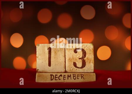 13 décembre vintage bloc calendrier en bois sur tissu rouge, festive bokeh lumières fond carte de voeux célébrer les vacances, anniversaire, enregistrer la date f Banque D'Images