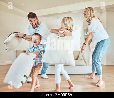 Une famille excitée qui se bat avec un oreiller. Famille caucasienne jouant avec des oreillers. Les enfants heureux s'affrontent avec leurs parents. Parents liant avec leur Banque D'Images